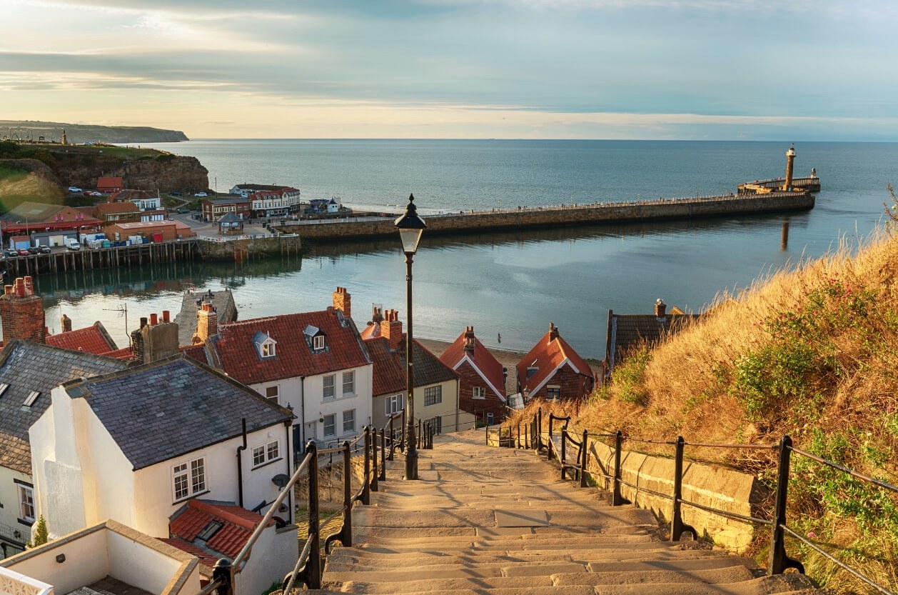 Looking down the 199 steps at Whitby to the harbour and the west pier lighthouse in low evening light